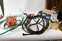 Various hoses, extension cords, and multi-plugs tangled together photographed on white background.