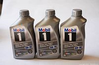 Photo showing three bottles of Mobil 1 5W-30 synthetic motor oil, two full and one partially used