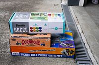 Stack of three outdoor games boxes: Franklin Bocce, Cornhole, and Pickleball Court with Net.