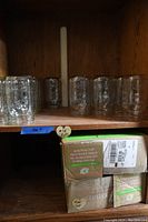 Shelf with multiple wide-mouth pint canning jars and boxes below.