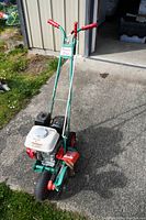 Full view of the Power Trim lawn edger showing the green frame, red handles, and motor mounted in front.