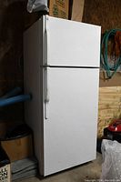 White top freezer refrigerator exterior showing front view with handles.