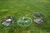 Photo showing all three crab pots with attached ropes, buoys, and bait cages on grass