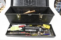Open black metal toolbox showing various small hand tools including screwdrivers, pliers, tape measure, and others in tray