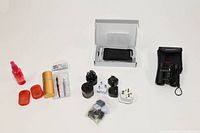 Wide shot of all items in the lot including solar charger, binoculars, plug adapters, and miscellaneous travel gear