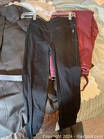 Photo of black workout pants laid on top of other clothing items including suit and sweatpants