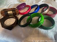 Overview of the group of colorful bangles arranged on fabric, showing varied designs and materials.