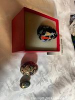 Three vintage collector eggs, one large decorative egg with a painted scene, displayed in red foam-lined box with two smaller eggs below.