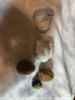 Top view of five vintage collector eggs on fabric background, showing various patterns and sizes.