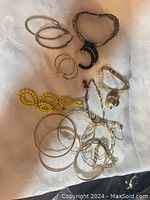 Top view of mixed jewelry pieces laid on fabric showing several bracelets, earrings, and a yellow beaded necklace.