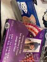 Photo showing the knitting loom set with five looms and the cardboard packaging, along with the Cribbage board game box