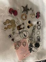 Image showing assorted vintage costume jewelry items spread out on a white fabric surface including earrings, rings, brooch, and a bracelet.