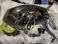Photo of silver plated tray holding several pieces of vintage costume jewelry including multiple watches, bracelets, necklaces, and rings.