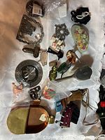 Overview of small vintage collectible lot including miniature figurines, jewelry pieces, dice, and decorative items on a white surface.