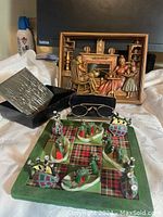 Full view of lot showing spectacles in case, Scottish game with tartan board and figurines, MCM metal wall art, and metal tray with etched lid