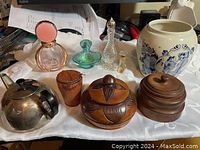 Photo showing the full vintage lot including perfume bottles, wooden containers, ceramic jar, and metal teapot arranged on white cloth.
