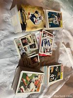 Photograph showing assorted stacks of vintage football, hockey, and basketball cards in varying sizes and designs lying on a surface.