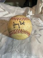 Front view of vintage baseball showing George Brett black ink signature on the ball's surface.