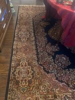 Full view of the Persian style area rug showing pattern, colors, and table on top.