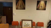 Wide view showing the signed watercolor painting seated on chairs and two ballerina mixed media artworks hanging on the wall above.