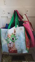 Photo showing a festive shopping tote with llama wearing holiday glasses and green handles with additional assorted totes behind