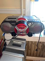 Front view of Sony boombox featuring CD player, radio tuner, cassette player, speakers, and control buttons with red and silver accents.