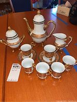 Full view of the entire tea set arranged on table including teapot, sugar bowl, creamer, cups with saucers.