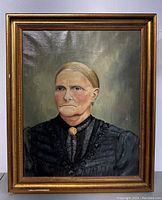 Full view of framed portrait of older woman in black dress with textured gold frame.