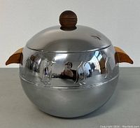 Front view of the polished metal ice bucket with animal silhouettes and wooden handles.