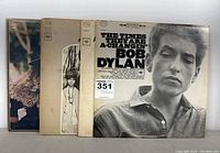 Five Bob Dylan vinyl records lined up showing front covers, including The Times They Are A-Changin' at the front