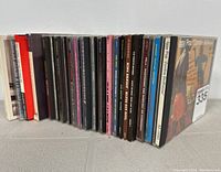 Side view of 21 music CDs showing album spine titles and colors