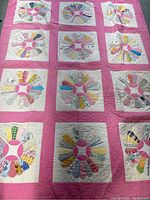 Full view of the quilt showing all Dresden Plate patchwork blocks with pink sashing and borders laid flat.
