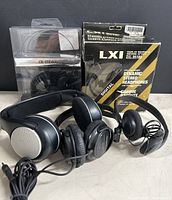 Three pairs of headphones shown together: LXI in box, Chateau headphones new in packaging, and Sennheiser headphones unboxed.