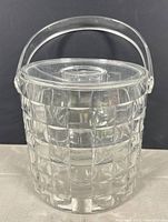 Front view of the clear lucite ice bucket showing the checkered texture, fitted lid, and handle.