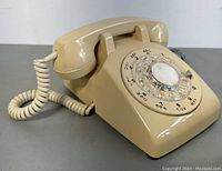 Front left angle showing rotary dial, handset, and coiled cord.