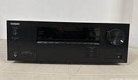 Front view showing Onkyo logo, display panel with source buttons, volume knob, and headphone jack.