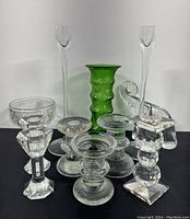 Lot showing all items together: pair of 10-inch crystal tapered candlesticks, green textured glass vase, smaller clear glass candle holders, pedestal bowl, and elephant figurines.