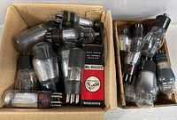 Two cardboard boxes filled with assorted radio electron tubes, some loose and some in original packaging.