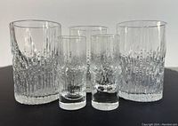 Five clear textured Scandinavian modern glasses shown on white background, two smaller shot glasses and three taller aperitif glasses.