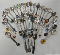 Full set of 39 souvenir and tea spoons fanned out on white background