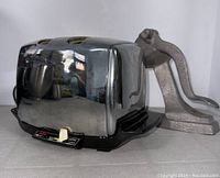 Side view of chrome Sunbeam toaster with black base; manual juicer behind it.