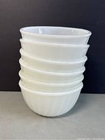Stack of six white Fire-King ovenware bowls.