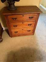 Full view of antique 3 drawer wooden dresser with metal handles and keyholes on each drawer.