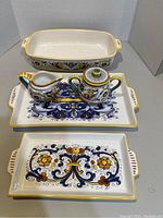 Set of three rectangular serving dishes, with floral and scroll designs in blue, yellow, and orange, plus matching creamer and teapot on top