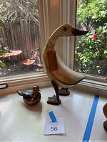 Both bird figurines displayed on a windowsill with natural light showing their relative sizes and details.