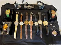 Overview of entire lot showing all watches and accessories laid out on black cloth.