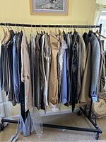 Full view of men's clothing rack with about 20 items including shirts, coats, jackets mostly XL in earthy neutrals and some patterns
