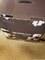 Box of Nespresso Vertuo cappuccino machine, showing box front with branding and images of coffee cups.