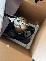 Metallic Nespresso Vertuo coffee machine seen from above inside box with foam packaging material.