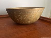 Side view of the brass bowl showing intricate engraved pattern on the exterior surface.
